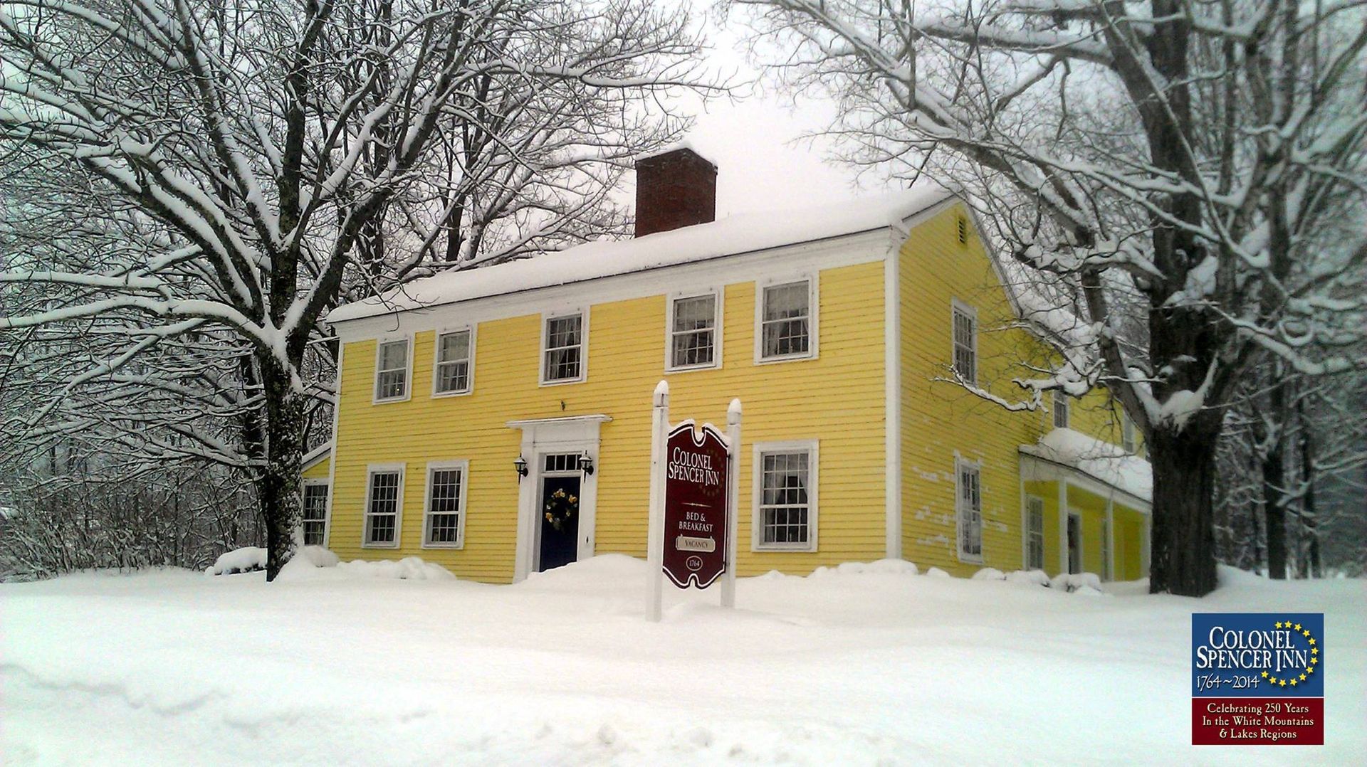 A large yellow house is covered in snow