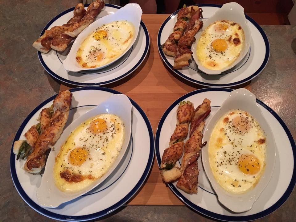 Four plates of food including eggs and bacon on a table