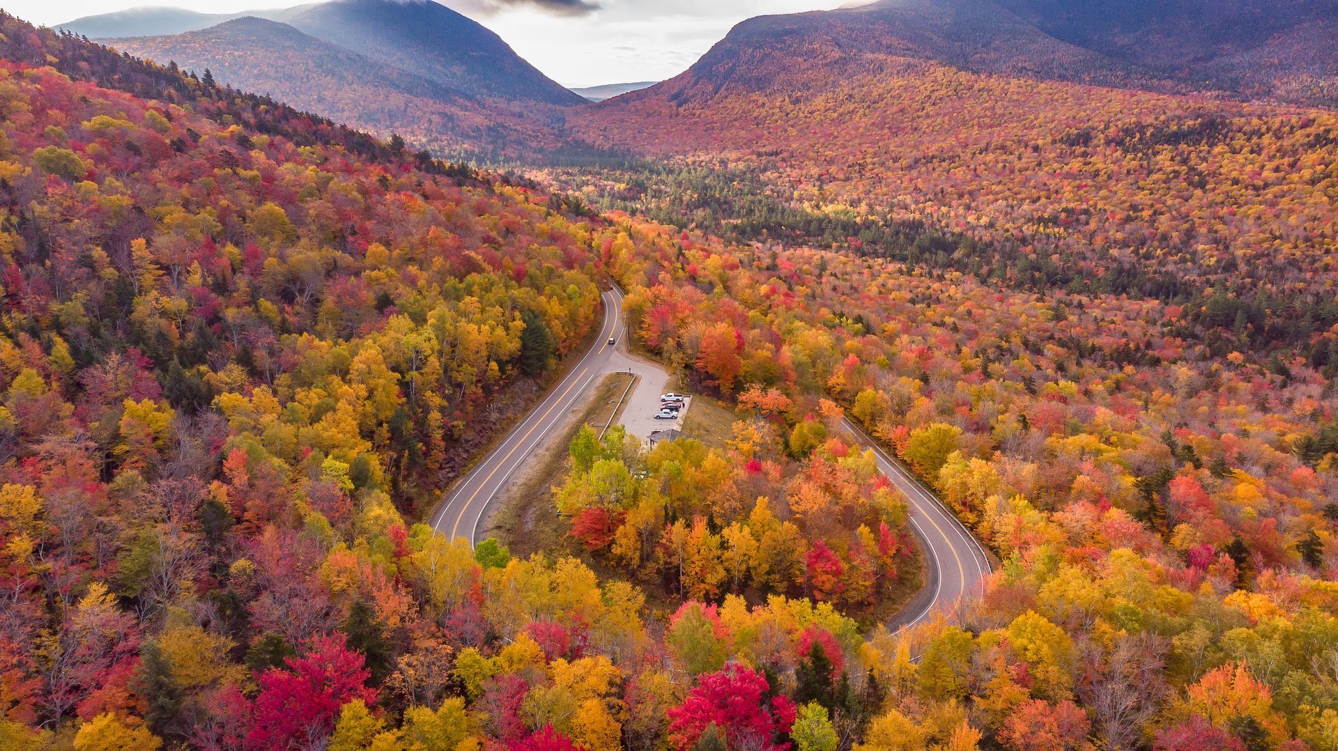 An aerial view of a road surrounded by colorful trees in the fall.