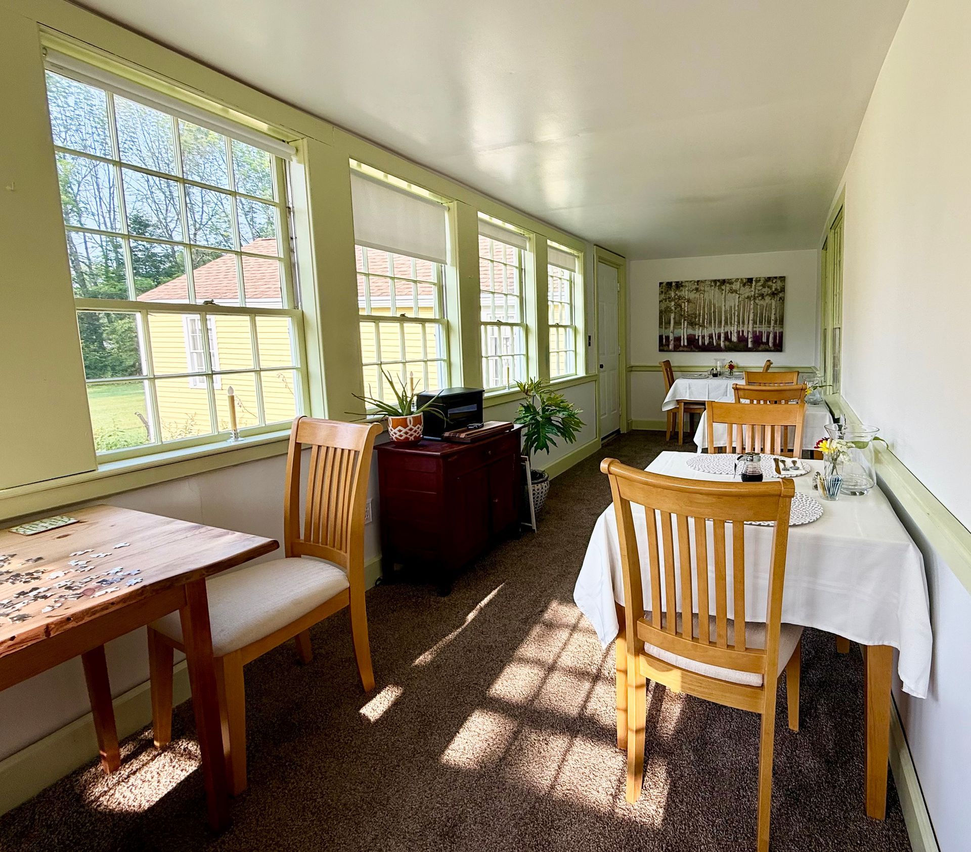 A room with tables and chairs and lots of windows