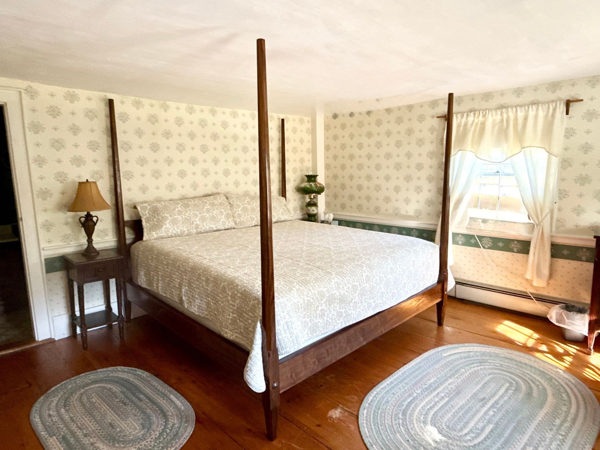 A bedroom with a bed , dresser , chair , lamp and windows.