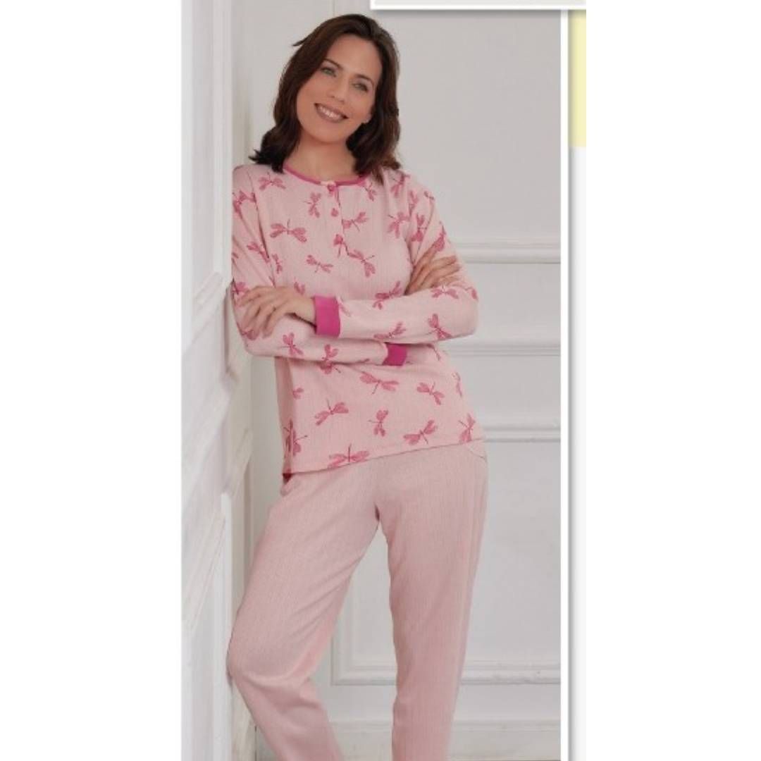 Una mujer con un pijama rosa está apoyada contra una pared.