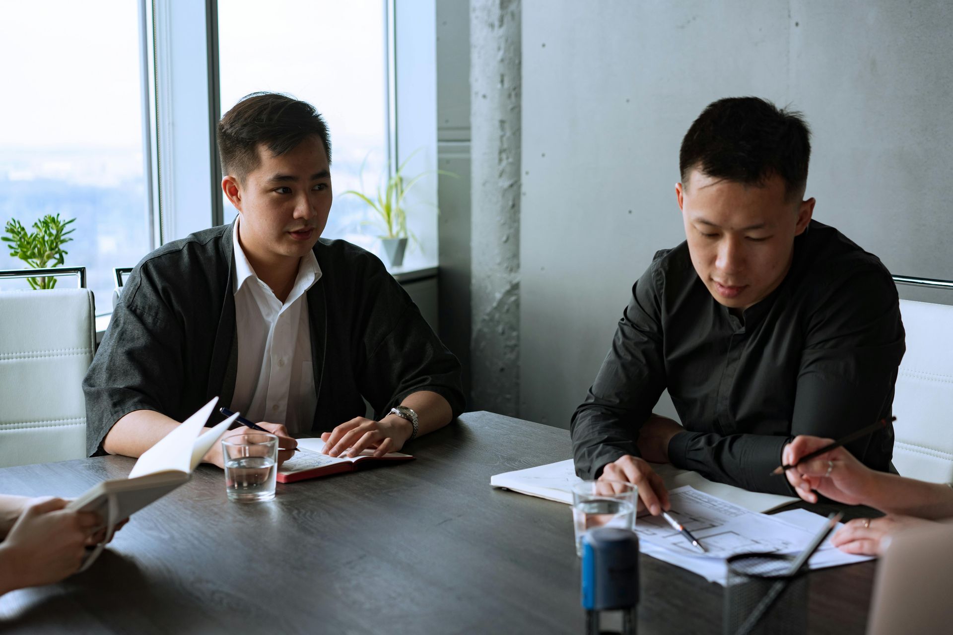 People sit at a modern office table, collaborating and reviewing documents during a meeting in a bright room.