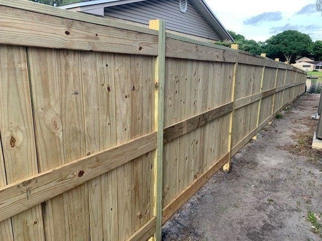 Wooden fence constructed of vertical planks and horizontal beams along a yard.