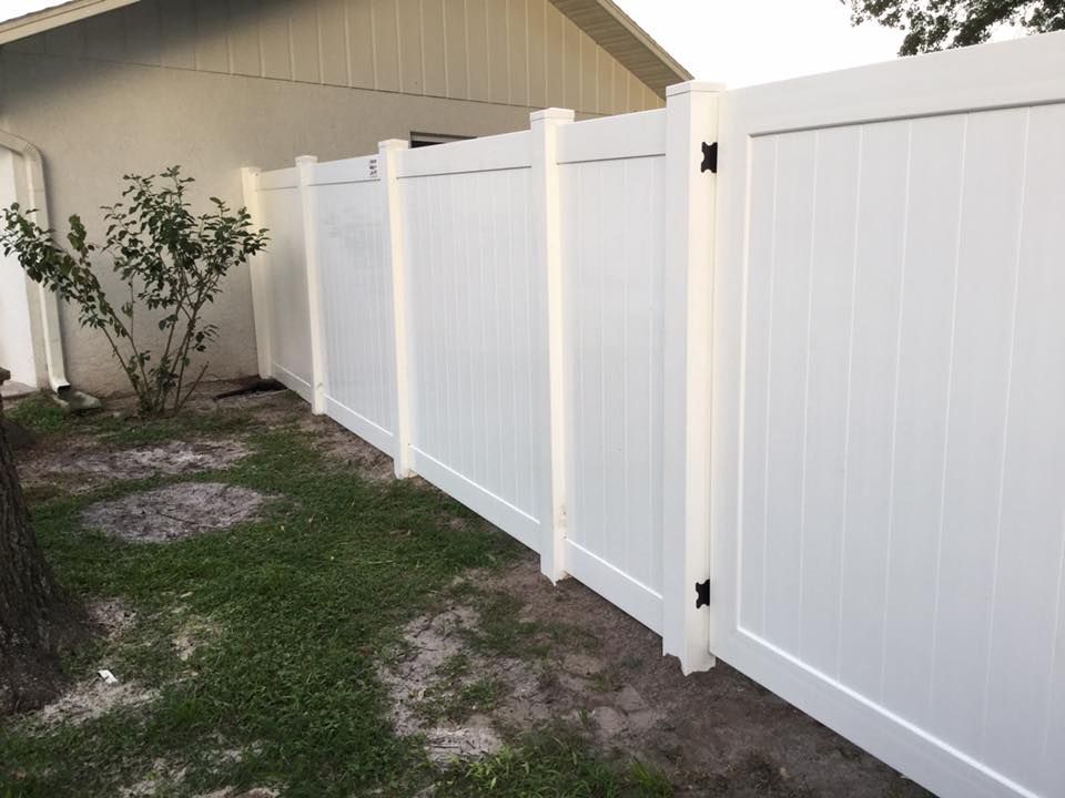 White vinyl privacy fence in a grassy yard against a house.