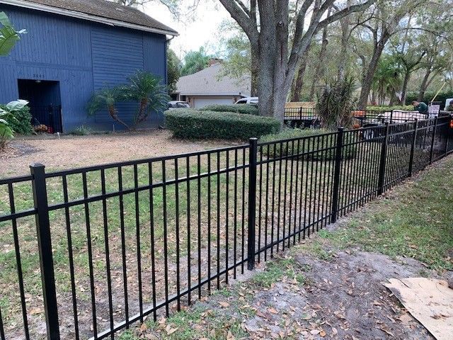 Black metal fence in a grassy backyard, separating the property.