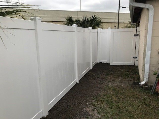 White vinyl fence with a gate, enclosing a yard.