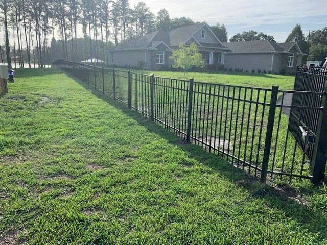 Black metal fence in a grassy yard, in front of a house.