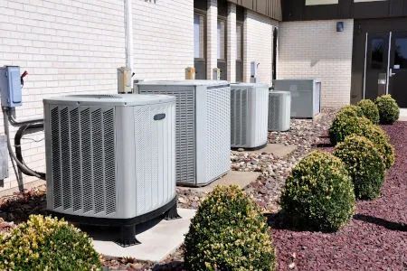 A row of air conditioners are sitting outside of a building.