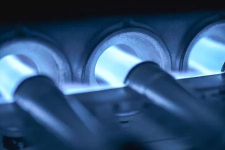 A close up of a gas burner with blue flames coming out of it.