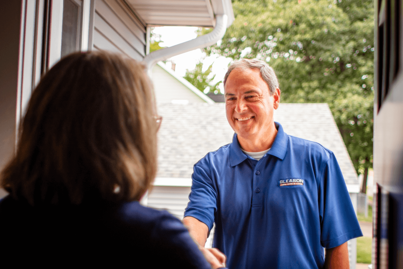 A man in a blue shirt is shaking hands with a woman in a doorway.