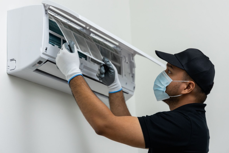 A man wearing a mask and gloves is cleaning an air conditioner.