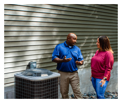 A man and a woman are talking to each other in front of an air conditioner.