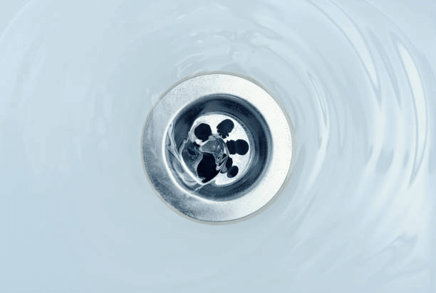 A close up of a sink drain with water running down it.