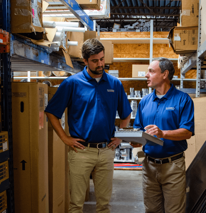 Two men in blue shirts are talking in a warehouse