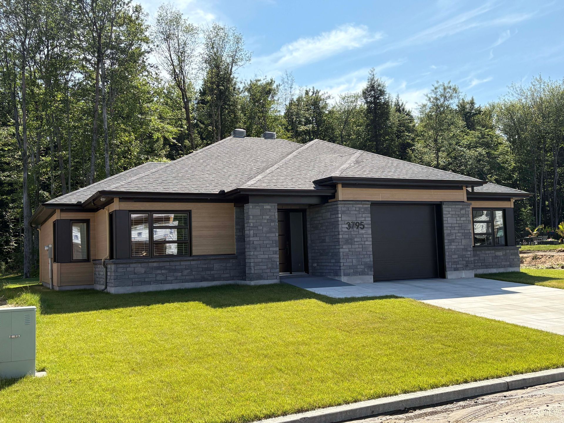 Une maison avec beaucoup d'herbe devant et des arbres en arrière-plan.