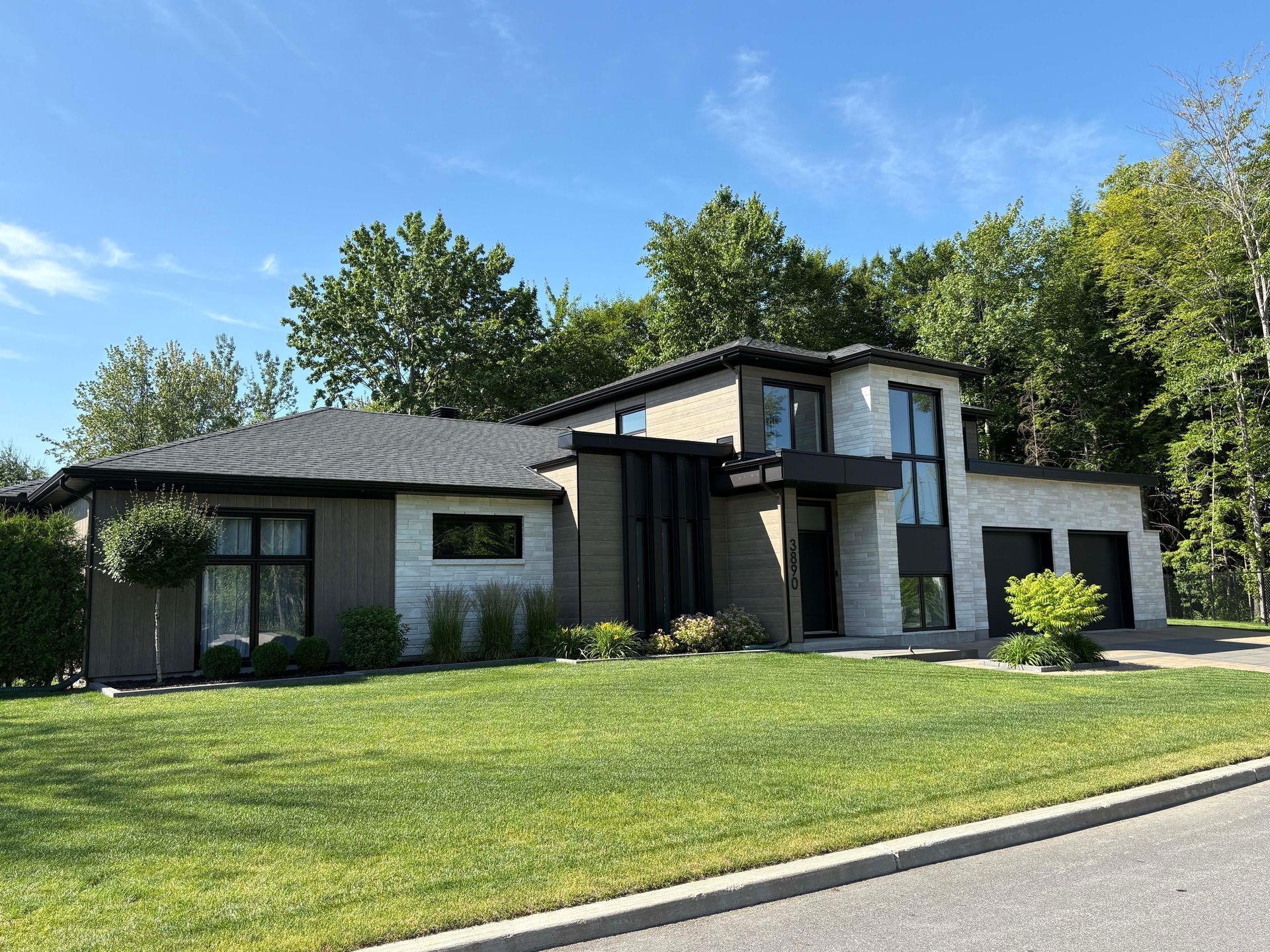 Une grande maison avec beaucoup de fenêtres est située au sommet d'une pelouse verte luxuriante.