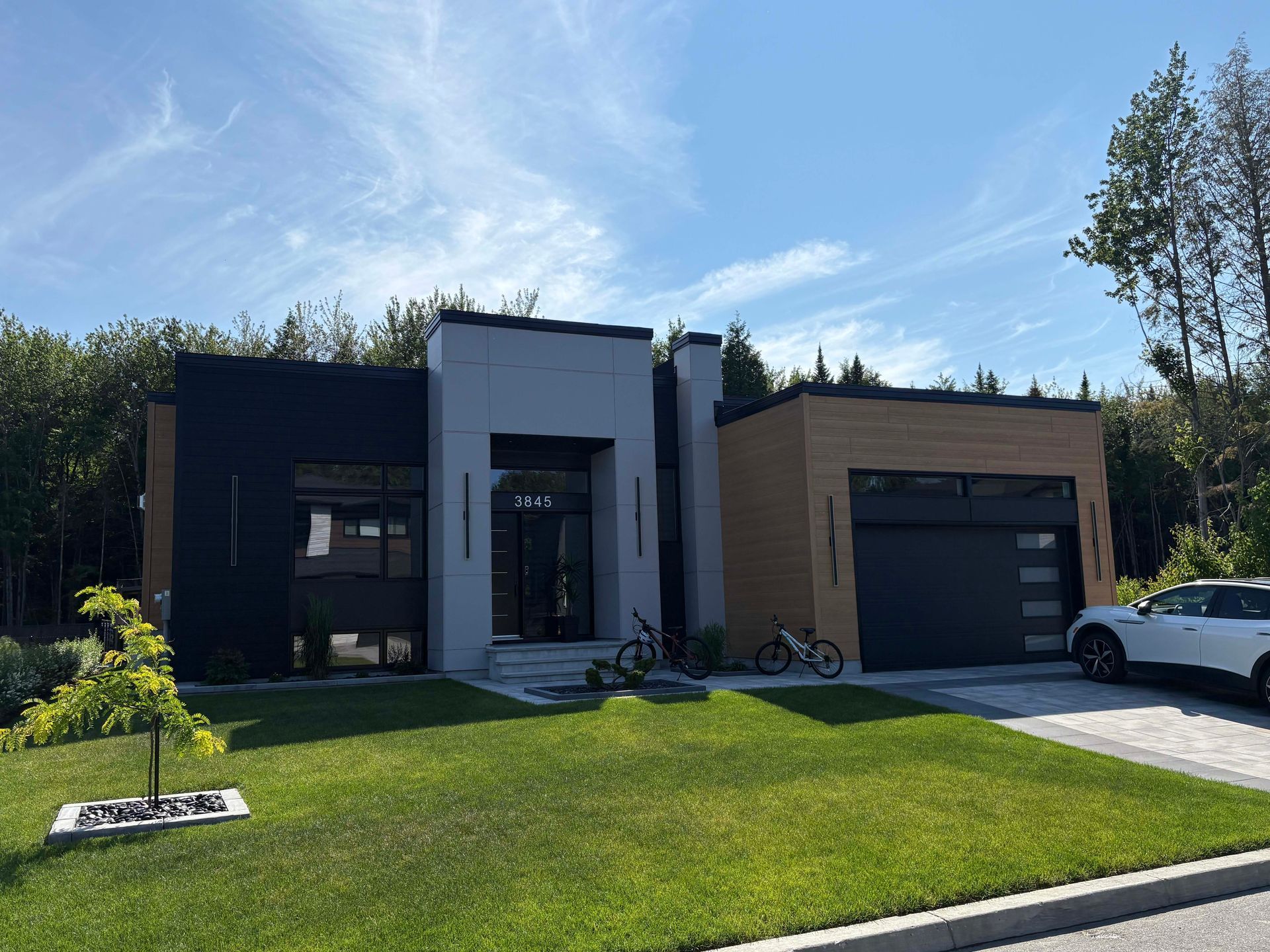 Une maison moderne avec une voiture garée devant.