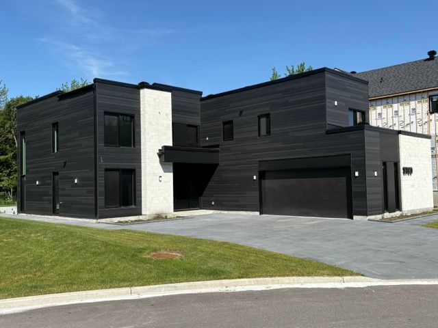 Une grande maison noire et blanche avec deux garages