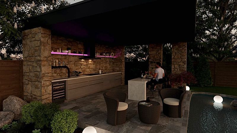 Un homme est assis à une table dans une cuisine extérieure à côté d'une piscine.