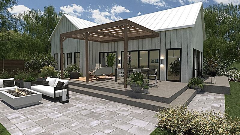 Une maison blanche avec un patio et un foyer devant.