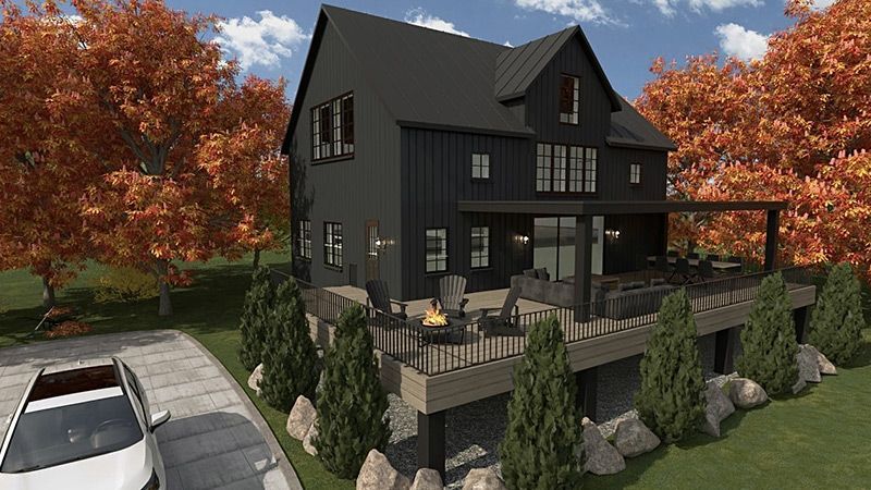 Une maison noire avec une voiture blanche garée devant.