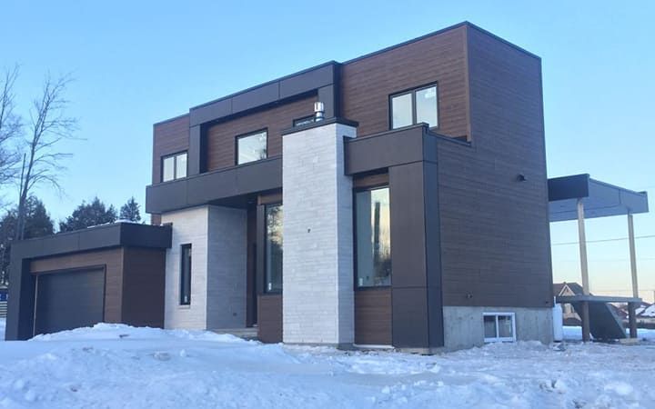 Une grande maison est située au sommet d'une colline couverte de neige.