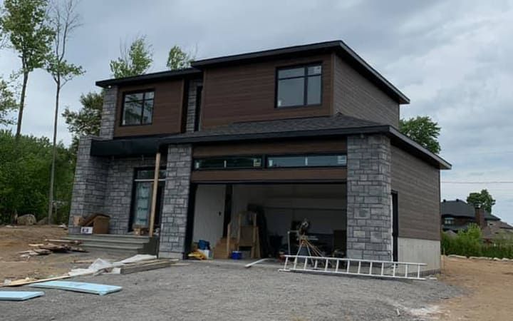 Une grande maison avec un garage en dessous est en construction.