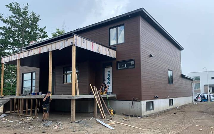 Un homme se tient devant une maison en construction.
