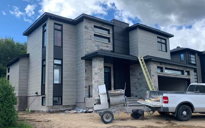 Un camion blanc est garé devant une grande maison en construction.