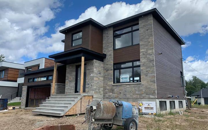 Une grande maison en construction avec une bétonnière devant.