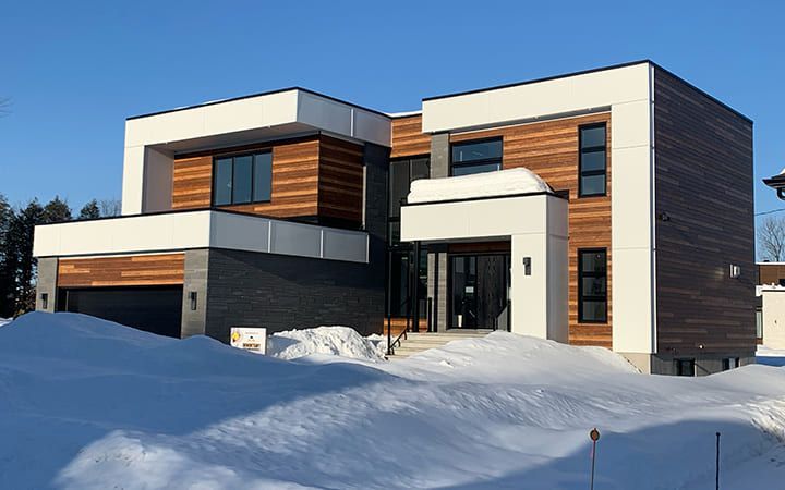 Une grande maison moderne est située au sommet d'une colline couverte de neige.