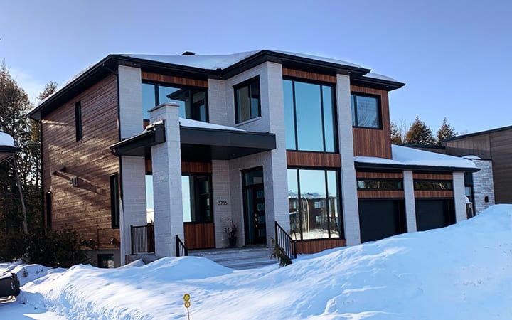 Une grande maison avec beaucoup de fenêtres est recouverte de neige.