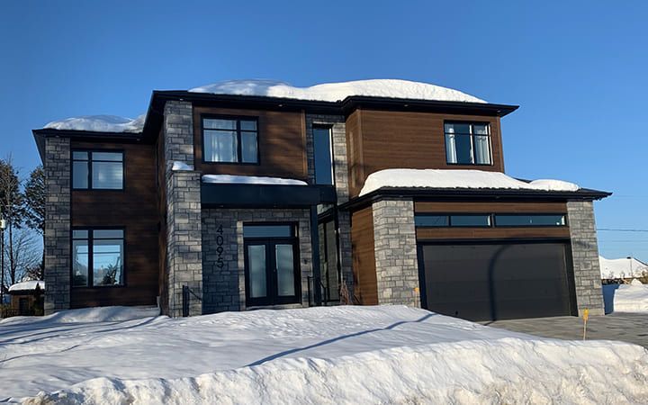 Une grande maison avec un garage est recouverte de neige.