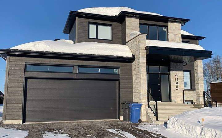 Une grande maison avec un garage est recouverte de neige.