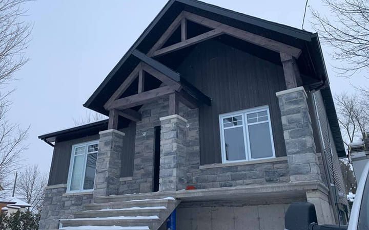 Une grande maison en briques avec un toit noir est en construction dans la neige.