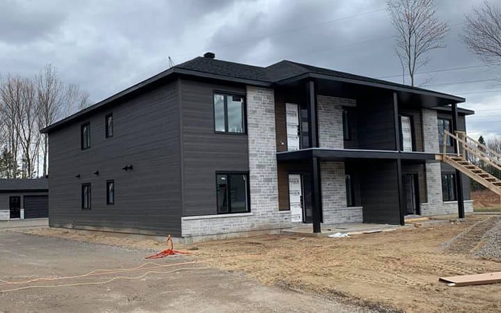 Une grande maison est en construction au milieu d'un champ.