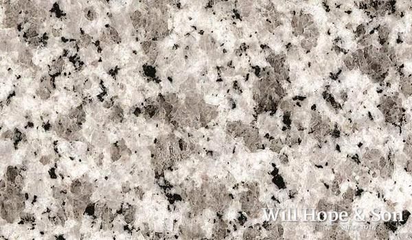 A close up of a white granite counter top with black spots
