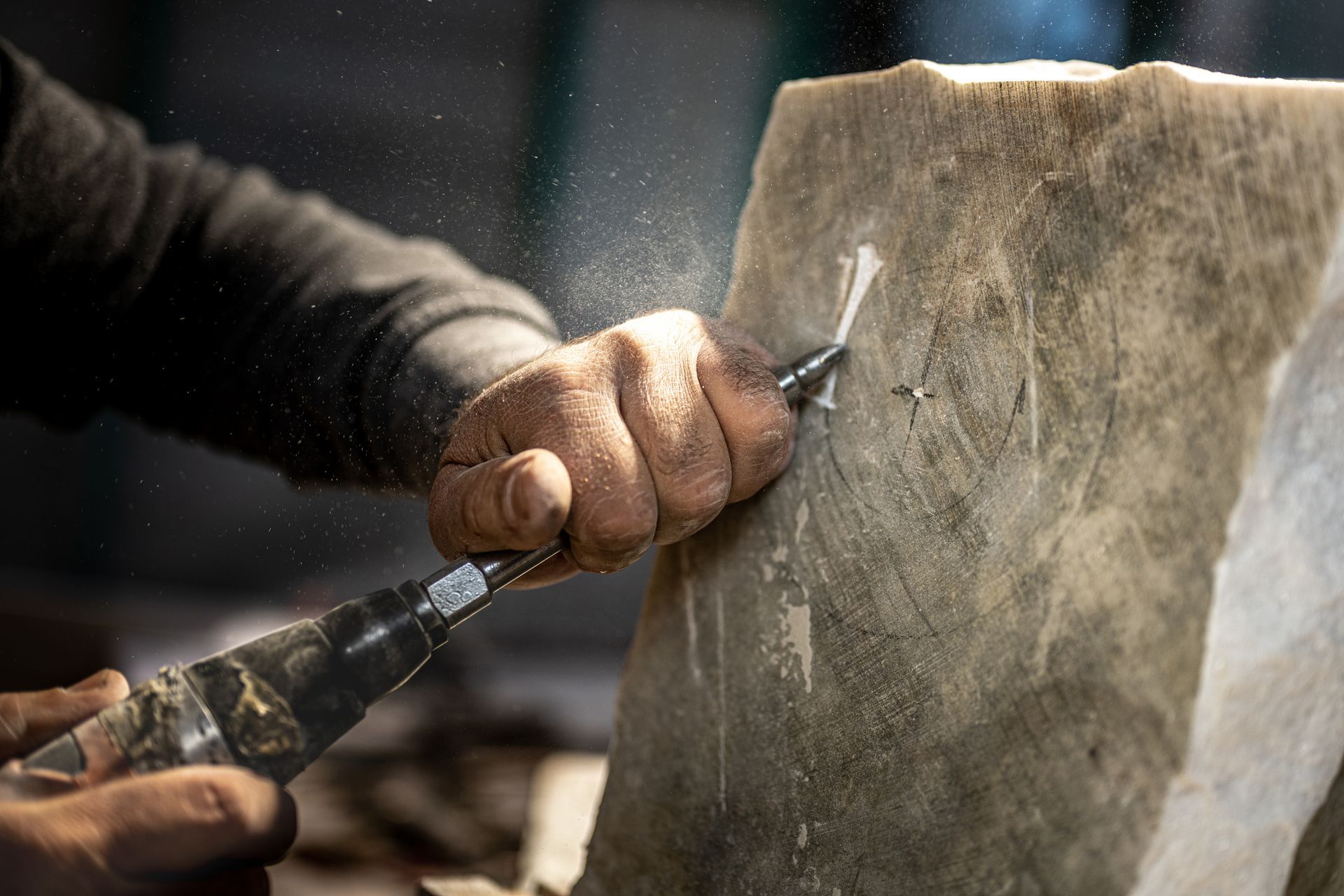 A person is carving a stone with an air drill.