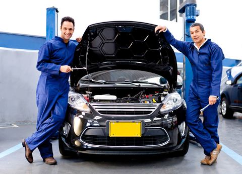 Mechanics standing in front of a car