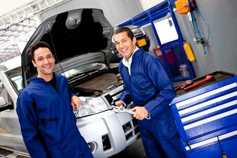 two car mechanics standing in front of a car