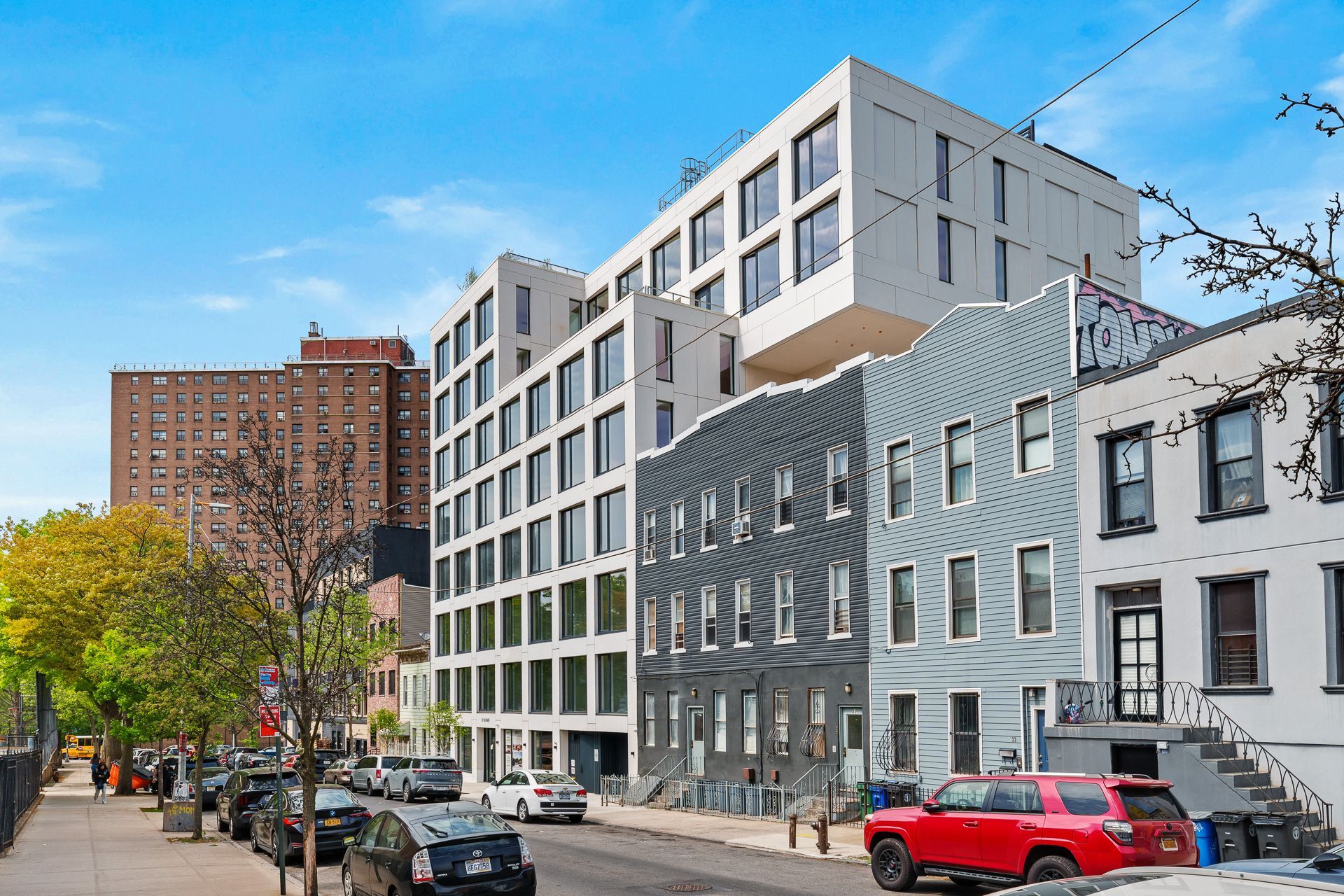 A red truck is parked in front of a large building.