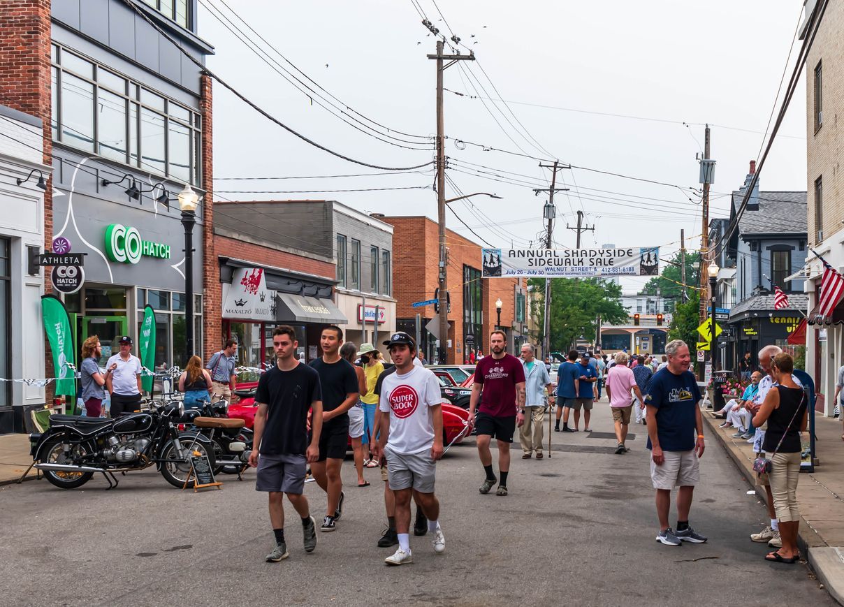 a group of people are walking down a street in a small town .