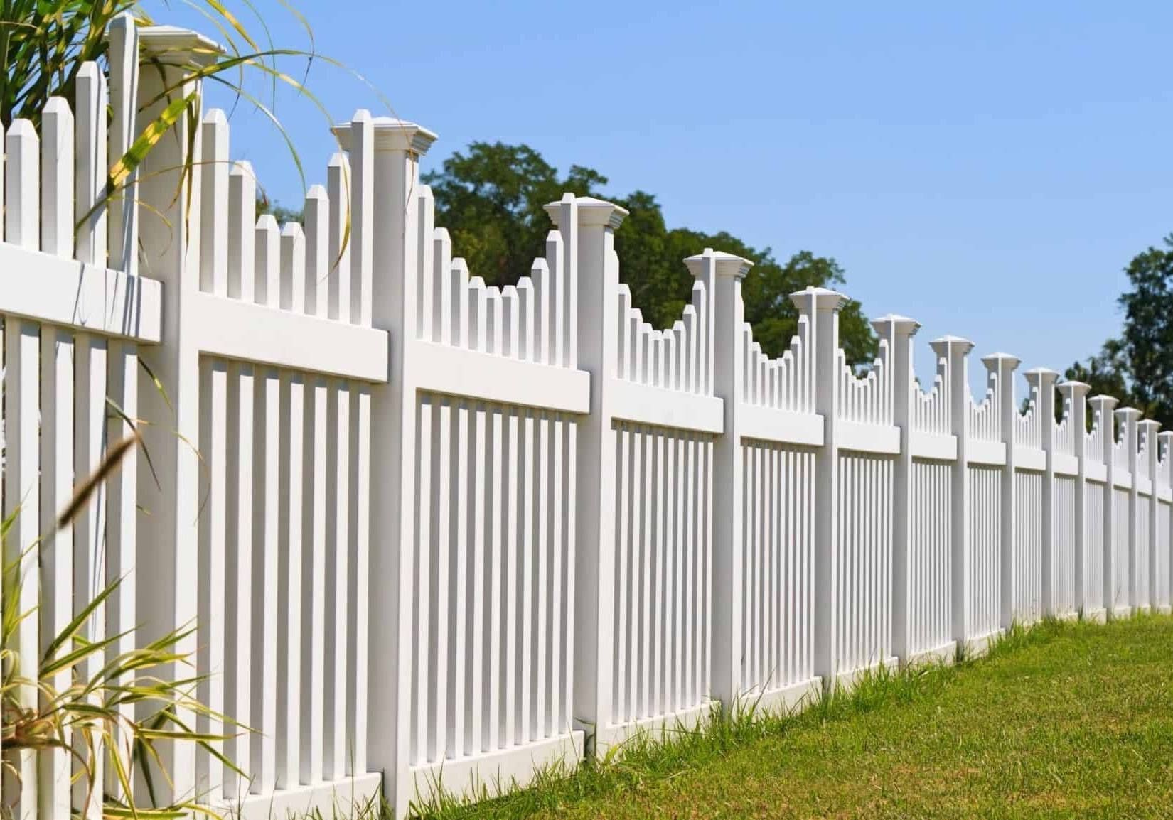 A white picket fence surrounds a lush green field.