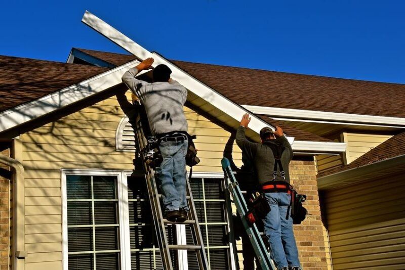 Two men are working on the roof of a house.