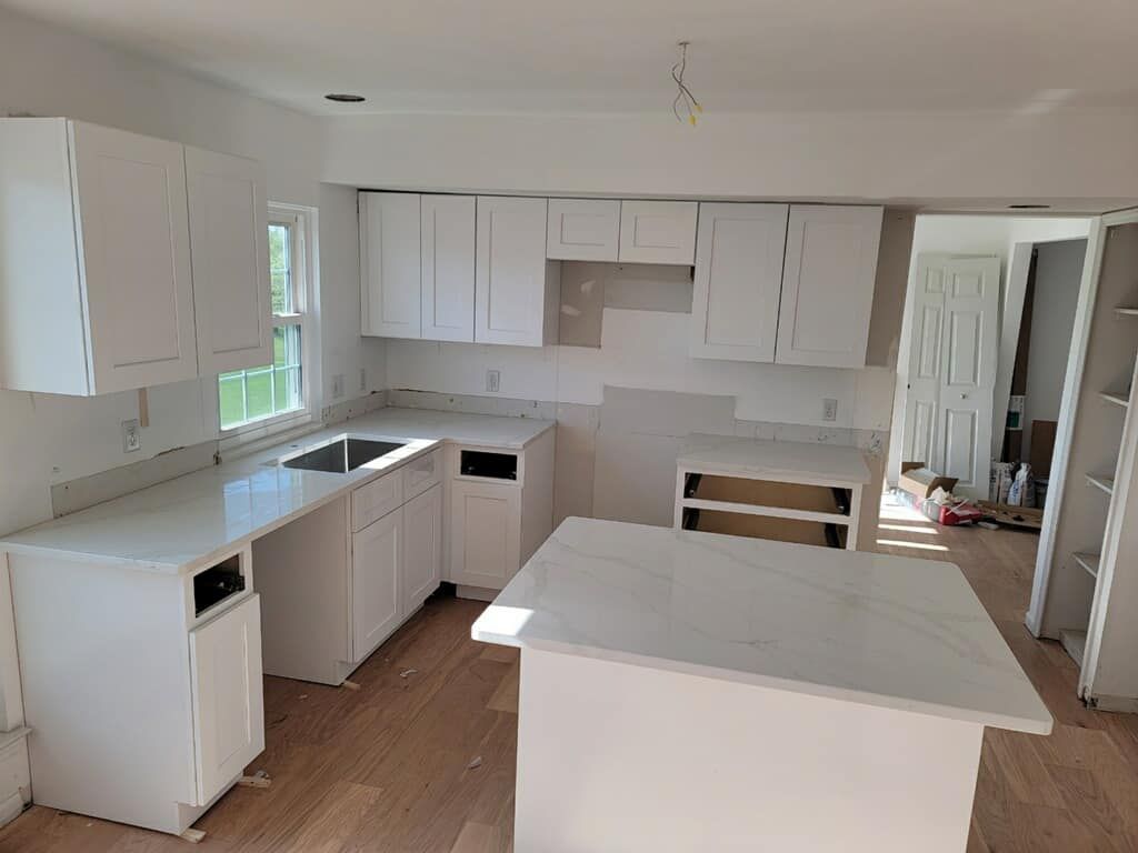 A kitchen with white cabinets and counter tops is being remodeled.