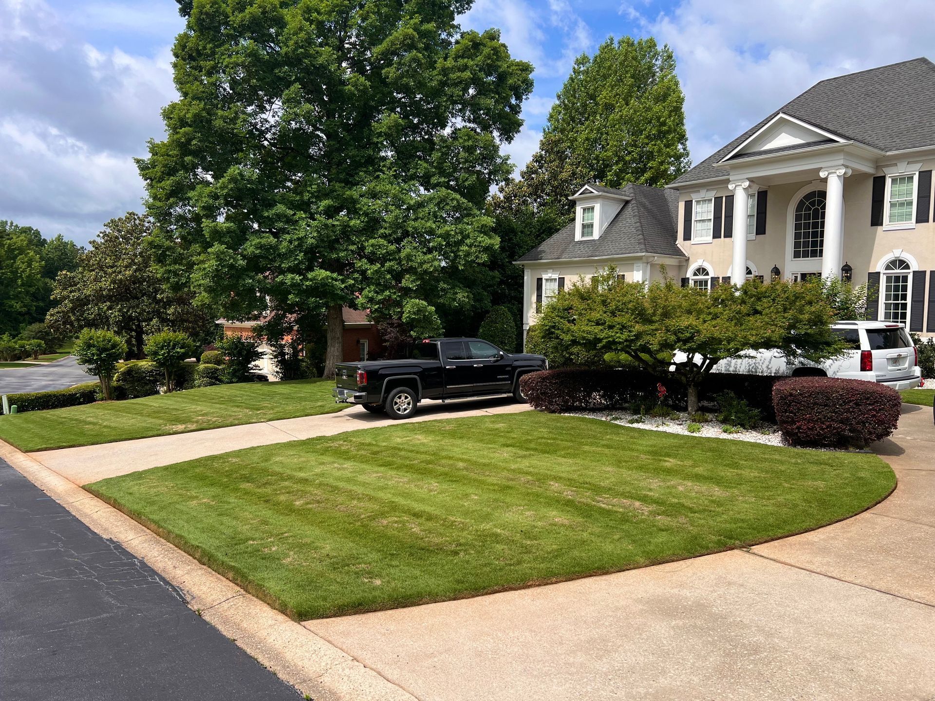 A black truck is parked in front of a large house.