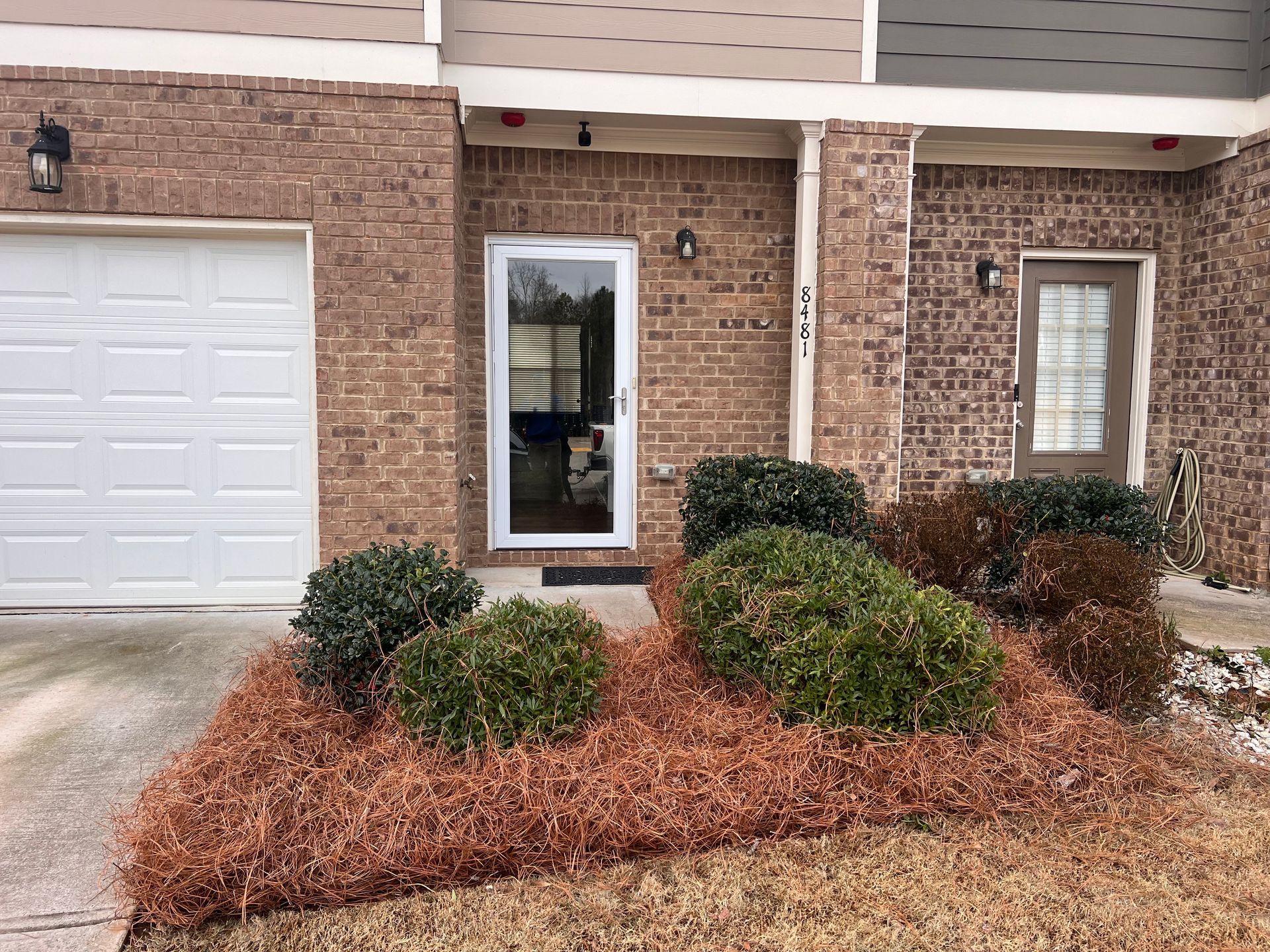 A brick house with a white garage door and a white door