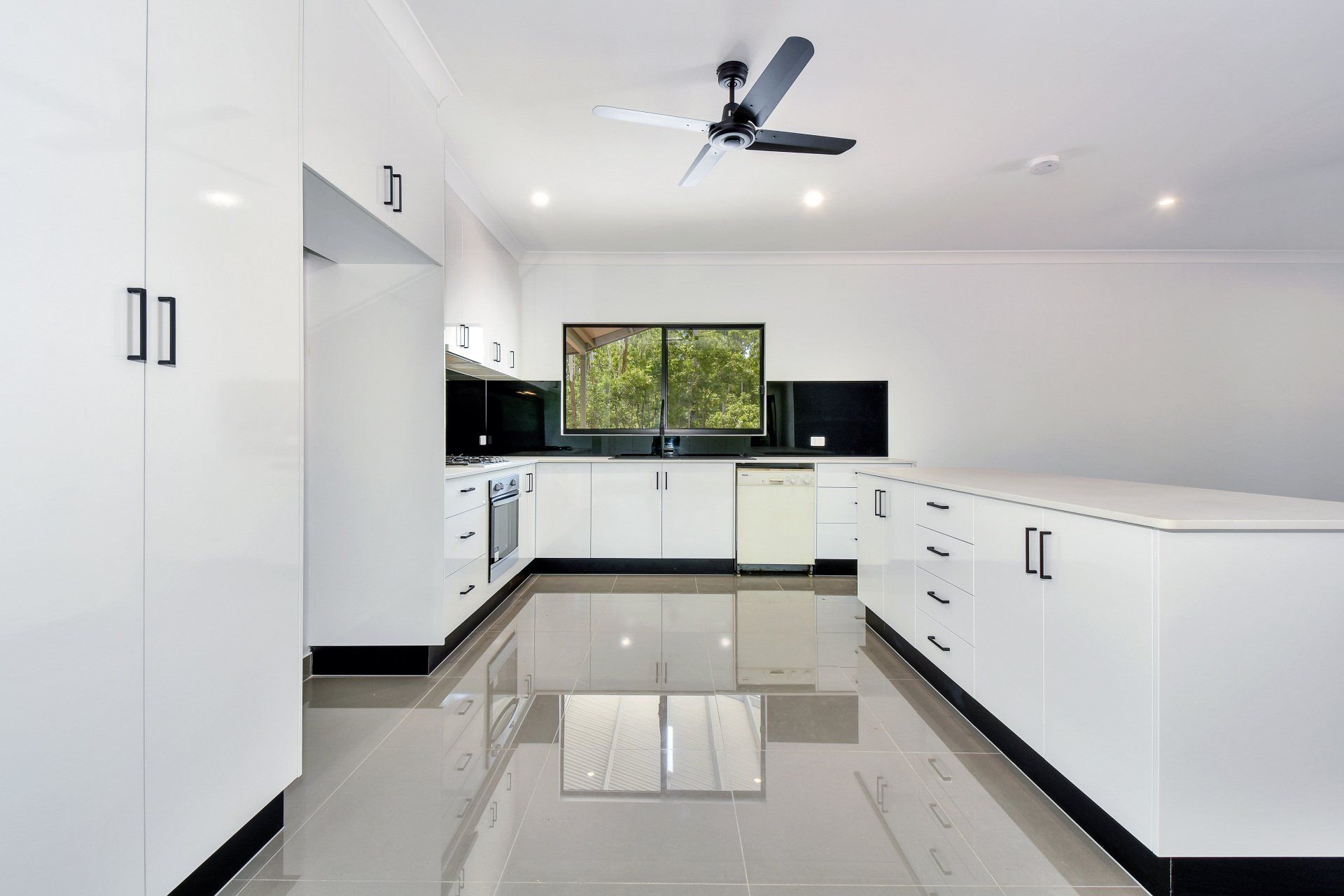 Bright white kitchen with black accents and a window.