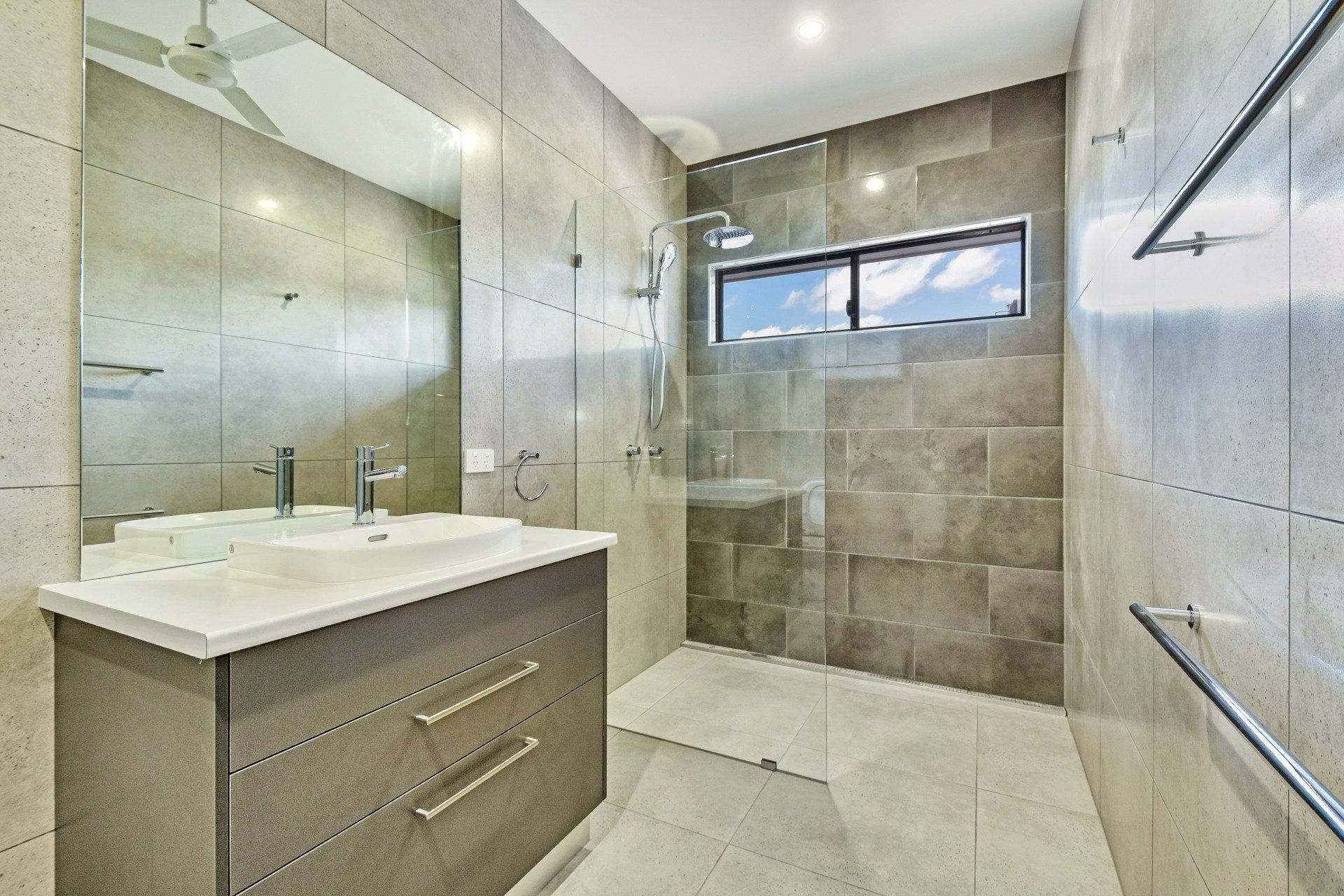 Modern gray bathroom with a vanity, shower, and a window.